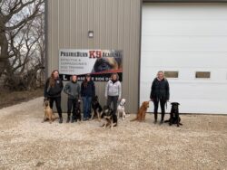 PrairieBurn K9 Academy's shadow student program students holding on their respective dogs in front of the dog training facility